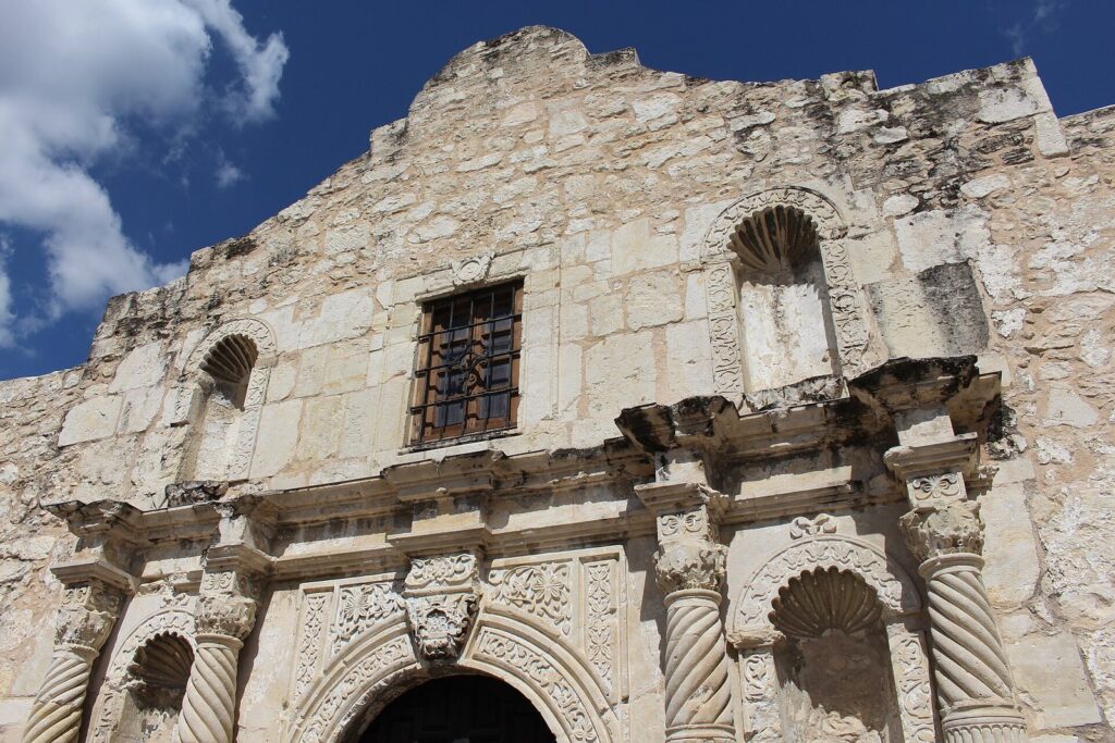 Carved limestone facade of the Alamo church under a blue sky in San Antonio