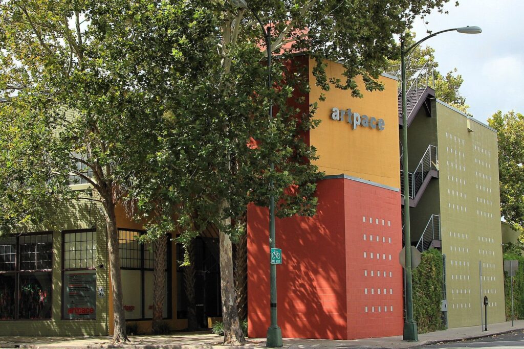 Artpace's colorful building on North Main Avenue with its orange, red and green facade behind street trees