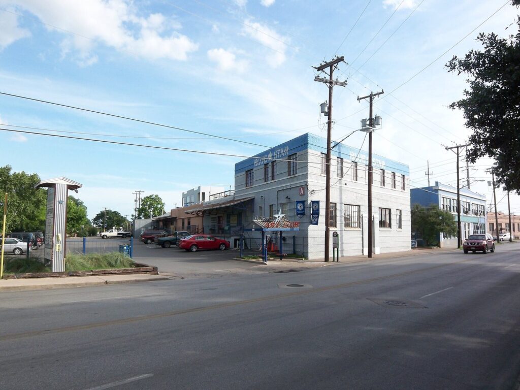The white and blue buildings of the Blue Star Arts Complex on a corner in Southtown under a blue sky