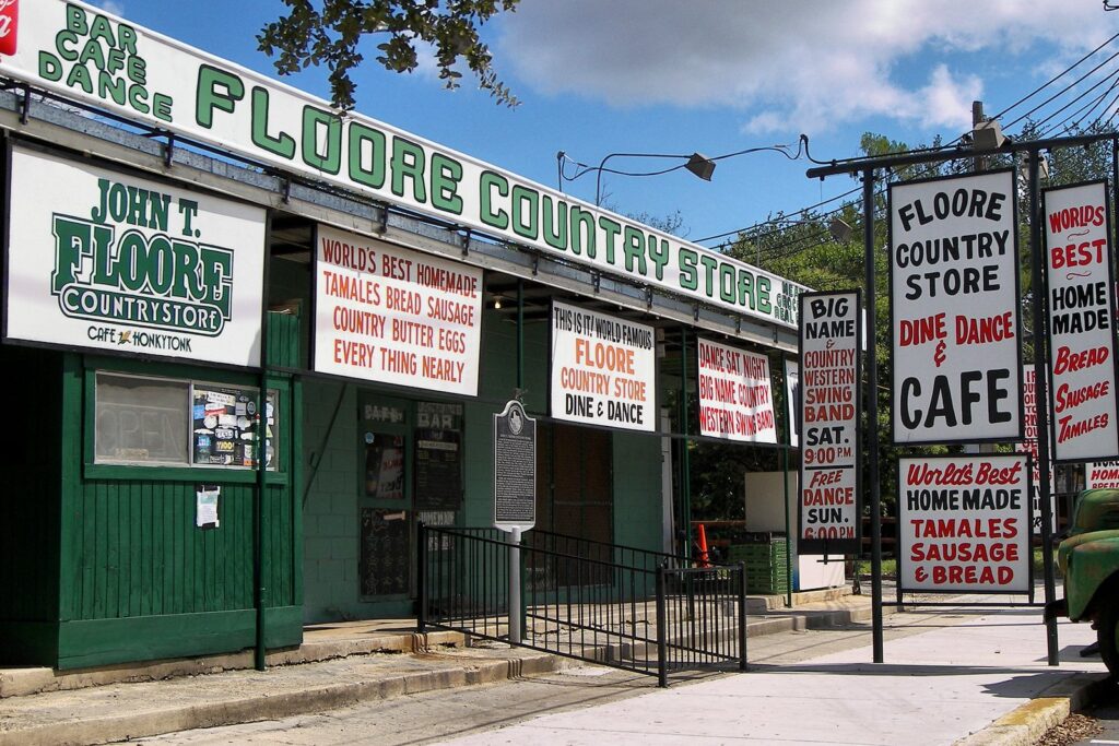 The green front of Floore's Country Store in Helotes covered in hand-painted signs advertising dancing, a cafe and homemade tamales