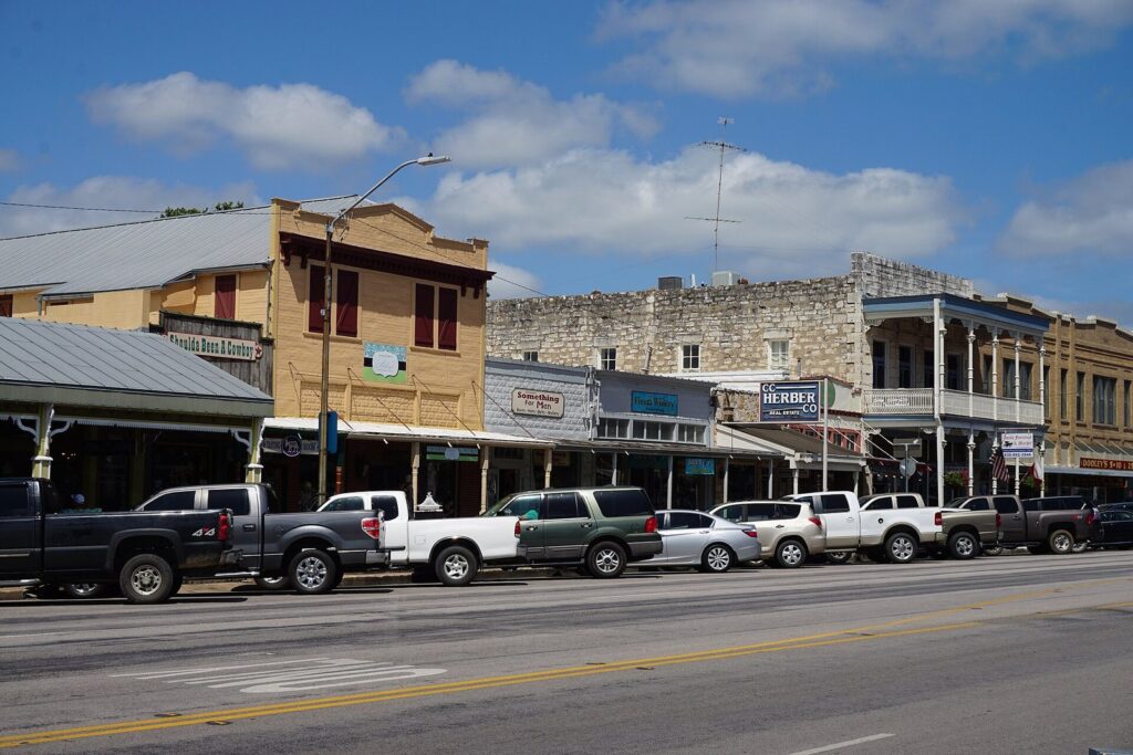 Fredericksburg's Main Street lined with 19th-century stone and wood storefronts, covered sidewalks and parked pickup trucks