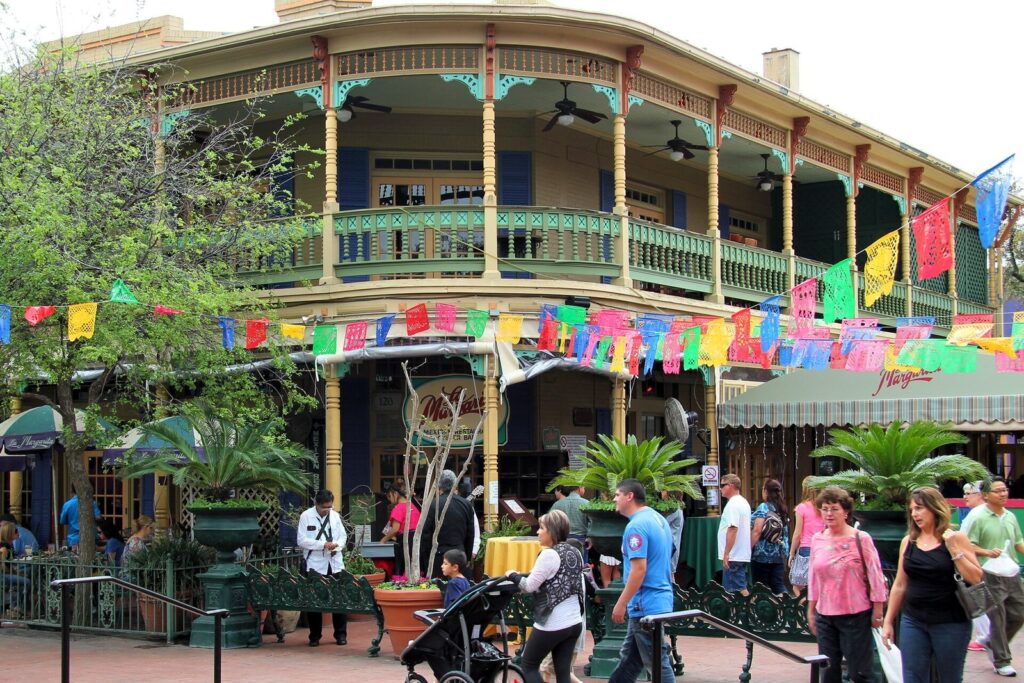 Strings of colorful papel picado over Market Square, with the balconies of Mi Tierra Café y Panadería behind