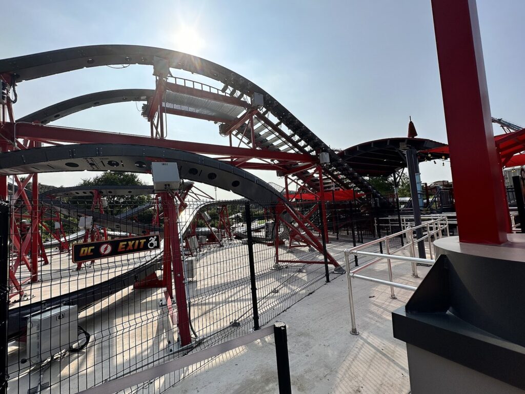 The red and gray track of the Kid Flash Cosmic Coaster curving through a station area at Six Flags Fiesta Texas