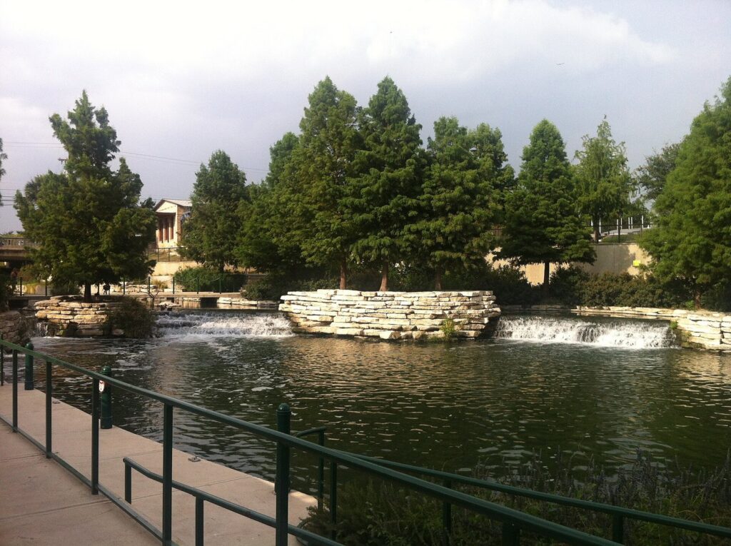 A low stone cascade and cypress trees at the head of navigation at the top of the Museum Reach
