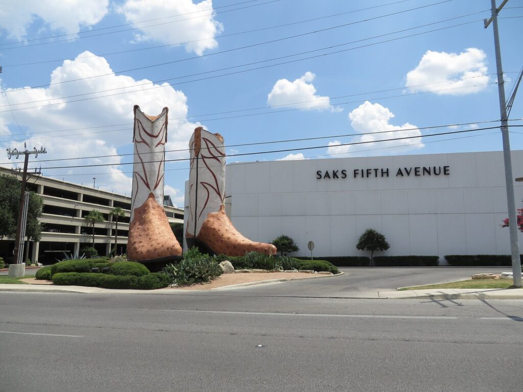 A pair of giant ostrich-skin cowboy boot sculptures outside North Star Mall, beside a Saks Fifth Avenue store