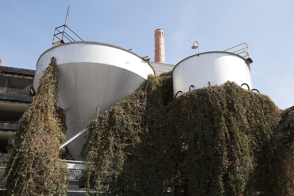 Old brewery storage tanks draped in climbing vines beneath the brick smokestack at the Pearl