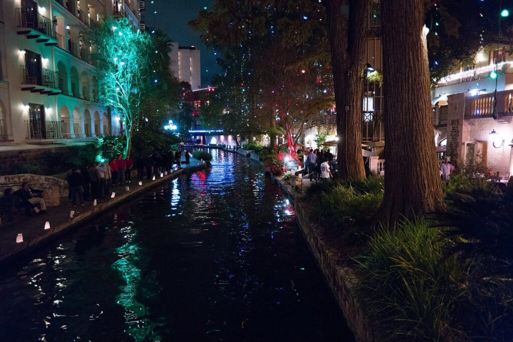 The River Walk at night with lights strung through the trees and buildings reflected in the water, the heart of San Antonio nightlife and romantic things to do