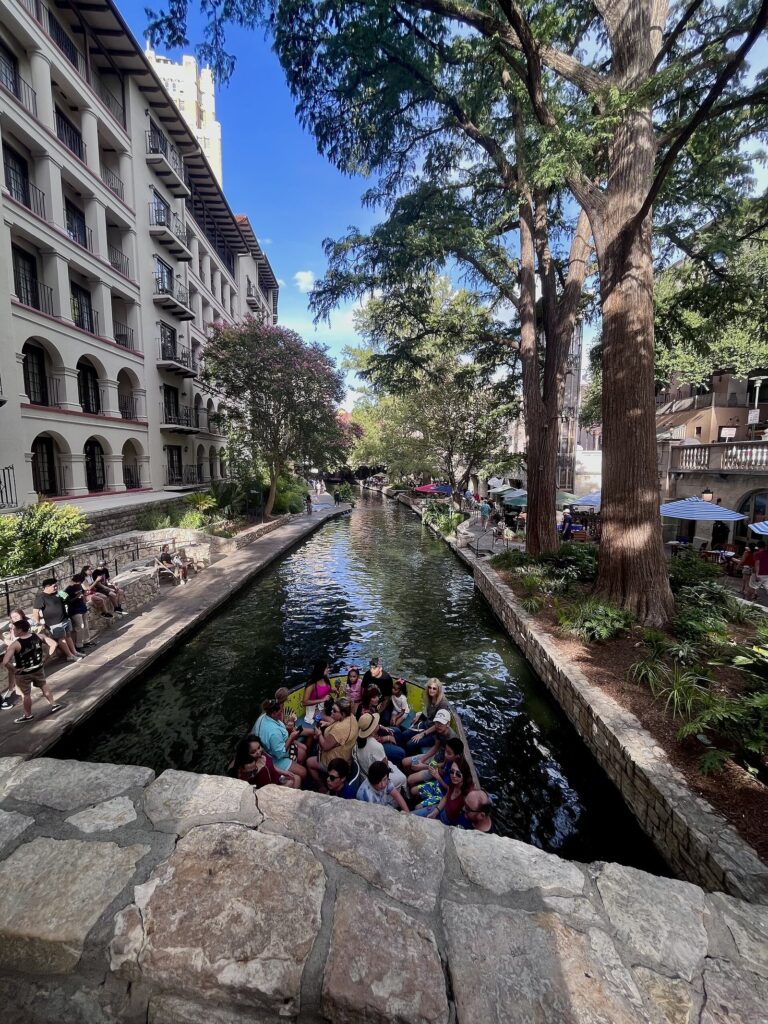 Tour boat passengers on the San Antonio River below the arched windows of Omni La Mansión del Rio