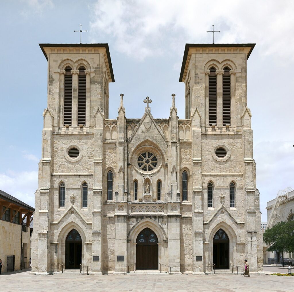 The twin Gothic Revival towers and pale limestone front of San Fernando Cathedral facing Main Plaza