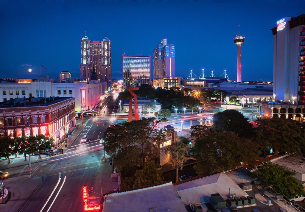 Downtown San Antonio at blue hour, with lit hotel towers, the red Torch of Friendship sculpture and the Tower of the Americas on the skyline