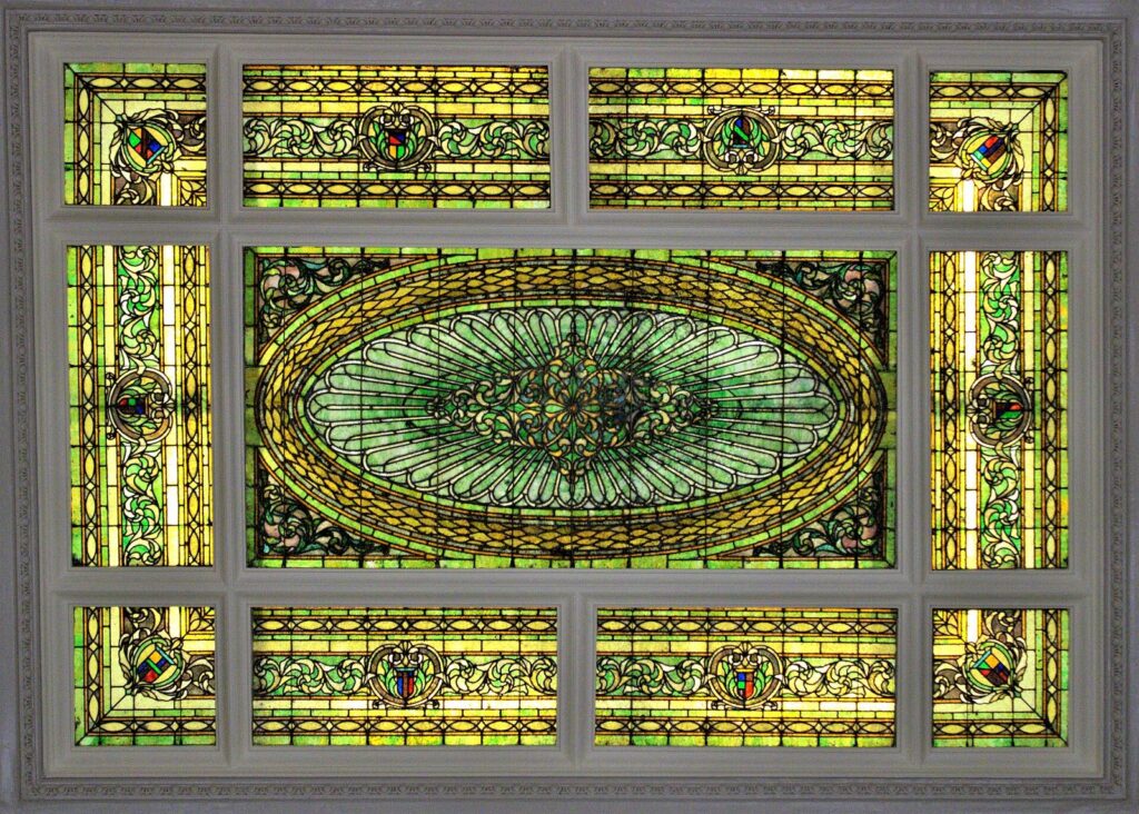 The ornate leaded stained-glass skylight in green and gold set into the lobby ceiling of the Menger Hotel