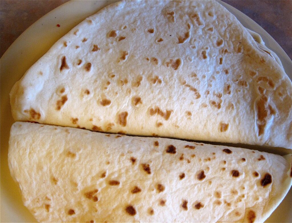 Two chorizo breakfast tacos folded in fresh, freckled flour tortillas on a plate in San Antonio